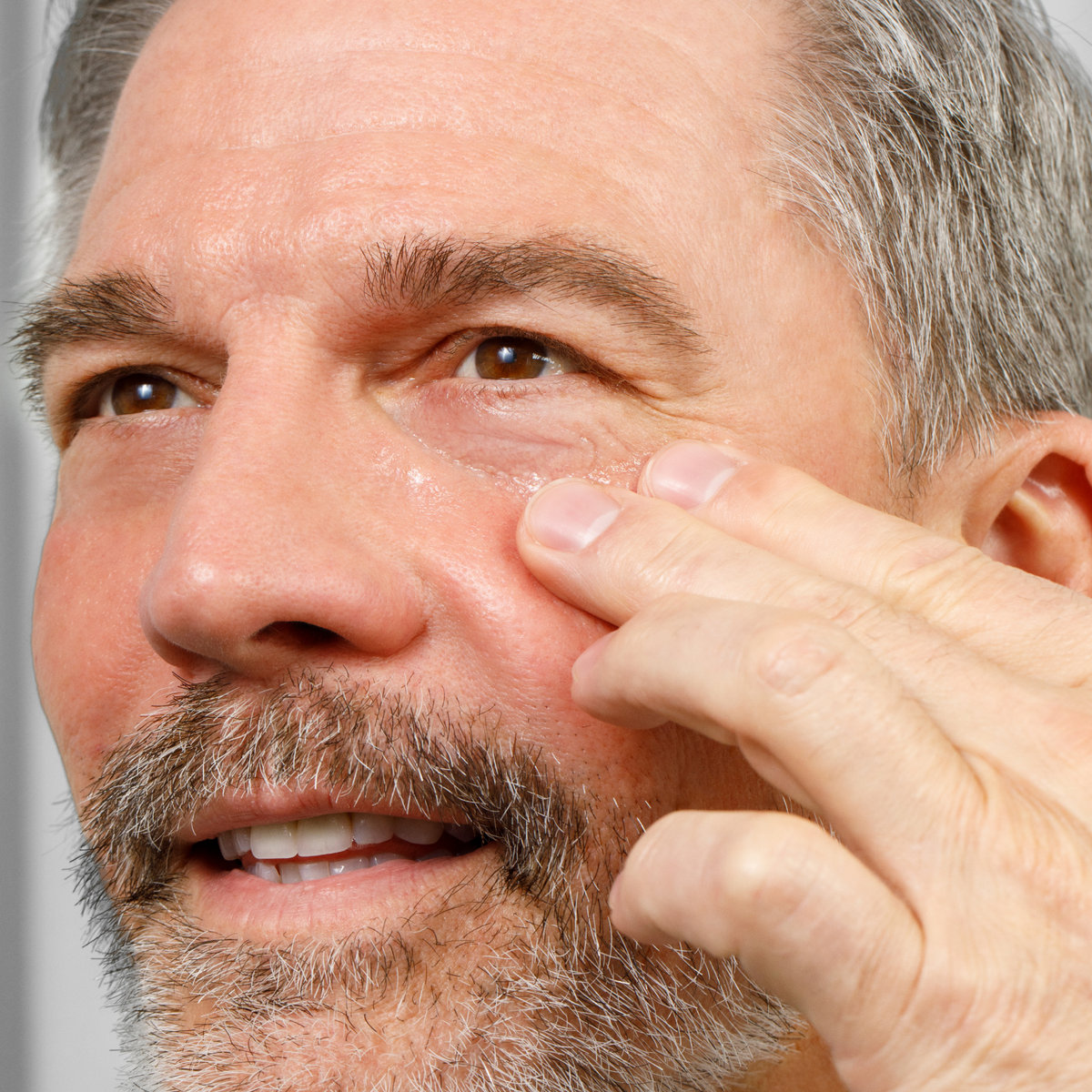 Middle-aged man applying anti-aging cream to face, skincare routine, men's grooming, facial care, healthy skin maintenance