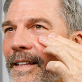 Middle-aged man applying anti-aging cream to face, skincare routine, men's grooming, facial care, healthy skin maintenance