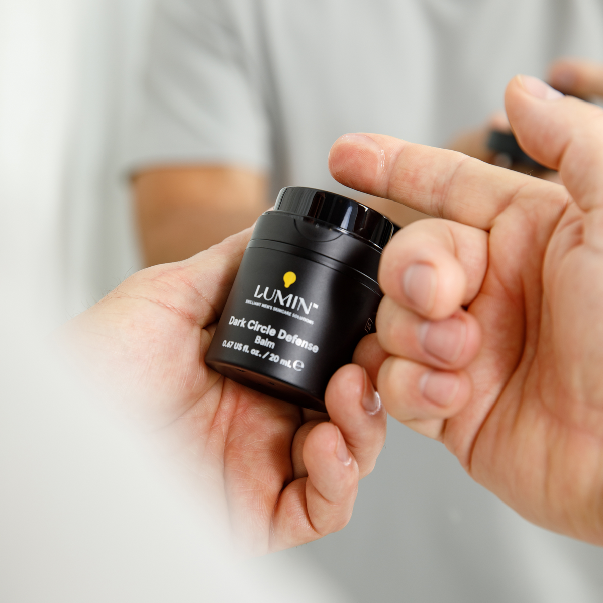 Hand applying Le NATIN black container skin cream on finger, skincare product for dry skin treatment, beauty care