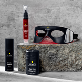 LUANIN skincare set with Daily Face Moisturizer, Wrinkle Defense Serum, and black eye mask on stone surfaces, gray concrete background.