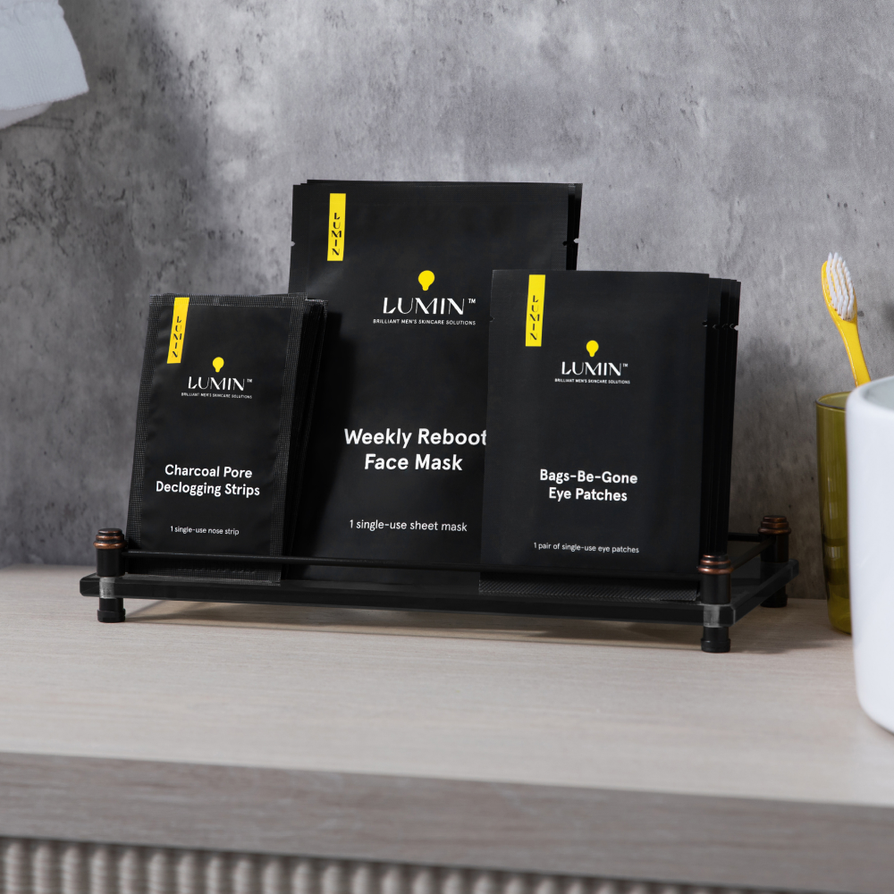 Black charcoal peeling, weekly reboot face mask, and eye de-gone eye patches skincare products on black rack with grey concrete wall background.