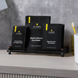 Black charcoal peeling, weekly reboot face mask, and eye de-gone eye patches skincare products on black rack with grey concrete wall background.