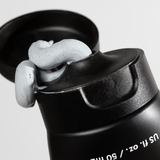 Black squeeze tube with open flip cap dispensing thick gray speckled skincare cream or facial mask