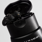 Black skincare tube with flipped cap dispensing thick black charcoal facial mask cream.