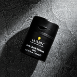 Lumin Dark Circle Defense Balm in black container on textured dark stone surface, men's skincare for eye care.