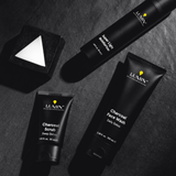 Lumin men's skincare set with charcoal scrub, face wash, super light moisturizer, and a geometric black soap bar on dark surface.