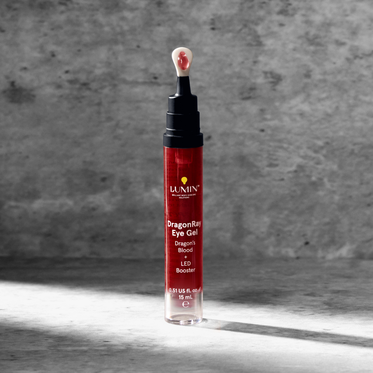 La Mer Energizing Eye Gel in sleek red tube with dropper, skincare product on textured gray surface, beauty and hydration serum.