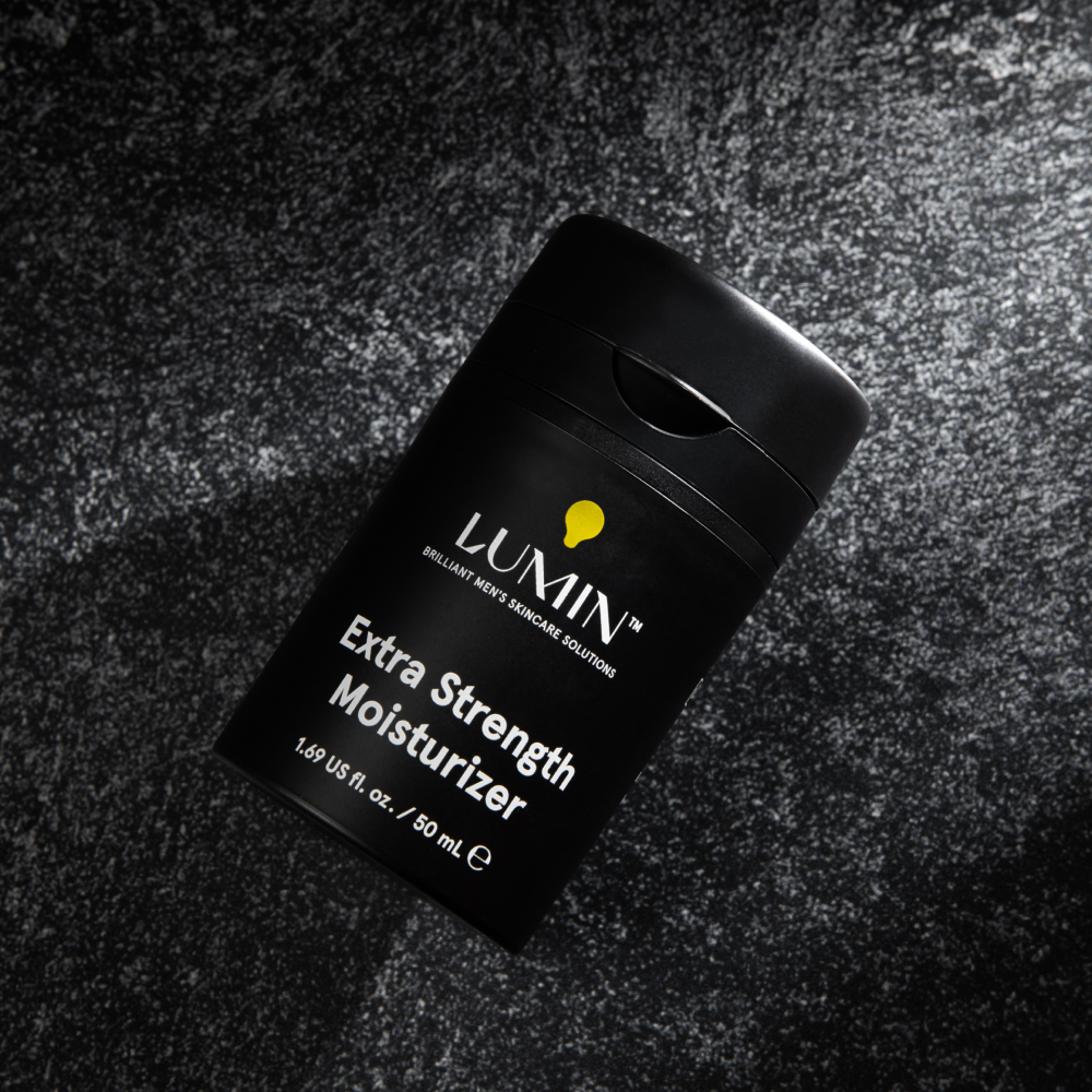 Lumin Extra Strength Moisturizer for men in sleek black 1.69 oz bottle on textured dark surface for skincare.