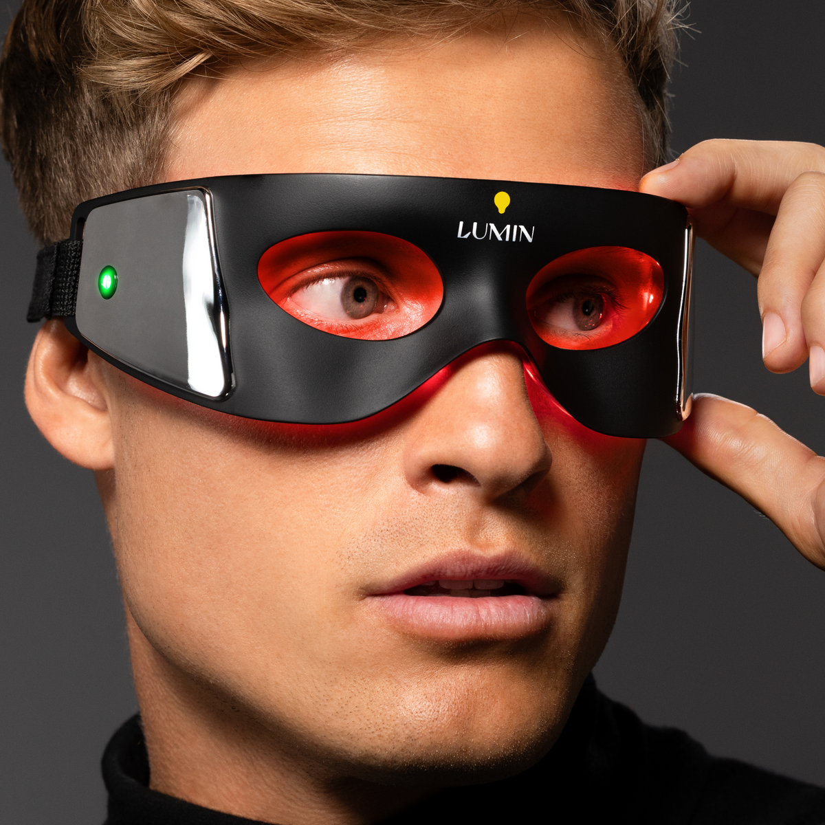 Black and red LED light therapy eye mask worn by a man, designed for relaxation and eye rejuvenation.