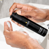 Hands dispensing white cream from Lumín Super-Light Moisturizer bottle above bathroom sink, skincare routine product.