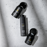 Lumin black skincare bottles and jars on concrete surface: Daily Face Moisturizer, Wrinkle Defense Serum, Dark Circle Defense Balm.