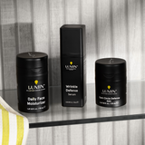 Lumin men's skincare trio with Daily Face Moisturizer, Wrinkle Defense Serum, and Dark Circle Defense Balm on glass shelf