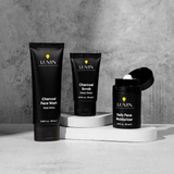 Lumin men's skincare trio with charcoal face wash, charcoal scrub, and daily face moisturizer on white platforms.