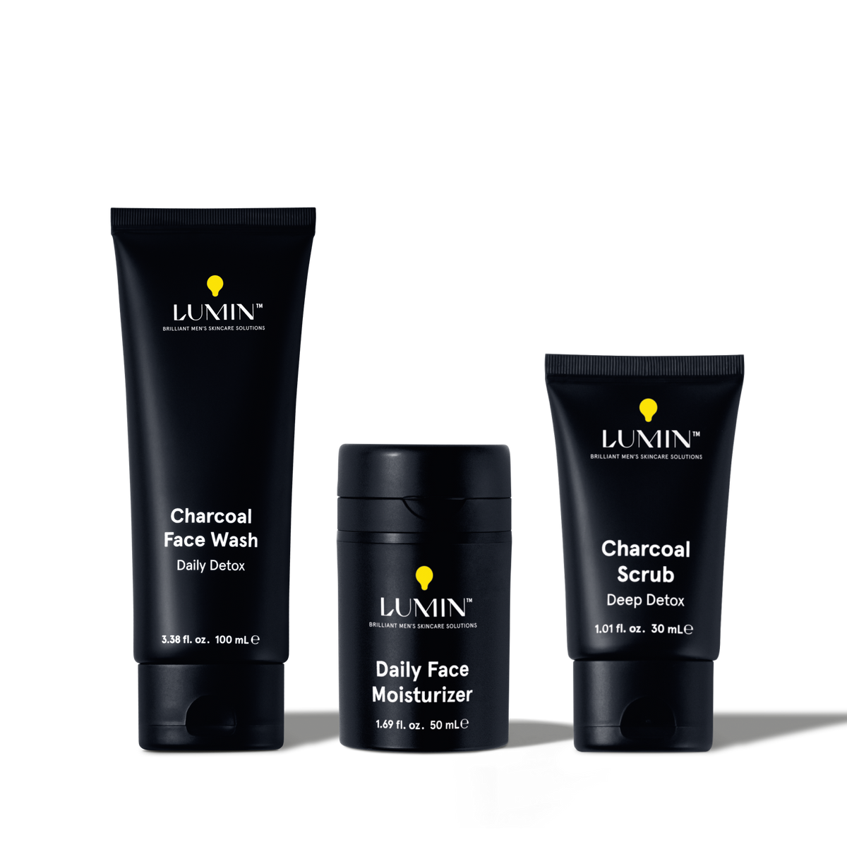 Lumin men's charcoal face wash, daily face moisturizer, and charcoal scrub skincare products in black packaging.