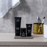 Lumin charcoal face wash, charcoal scrub, and instant redness corrector skincare products on bathroom counter with toothbrushes in holder.