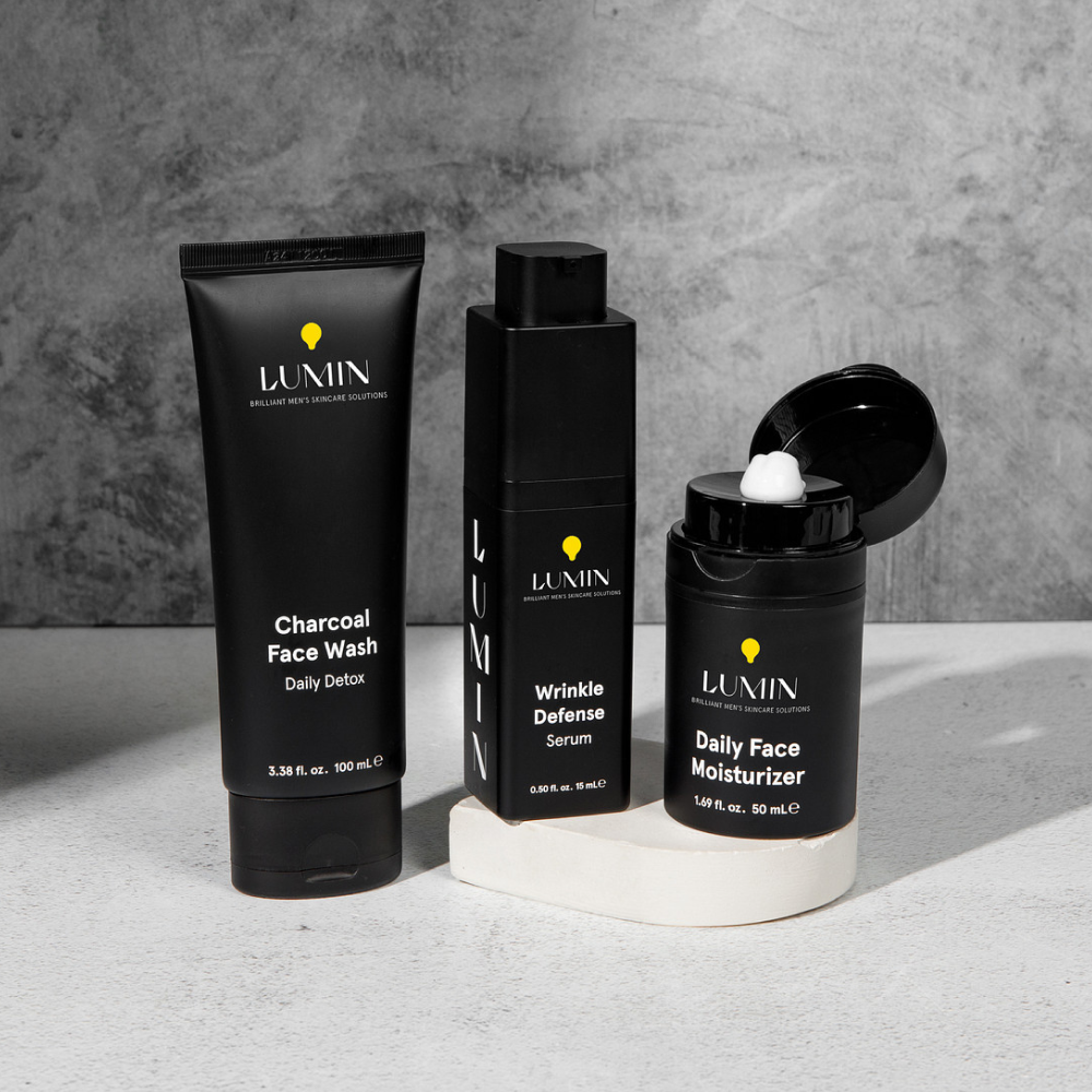 Lumin men's skincare trio: Charcoal Face Wash, Wrinkle Defense Serum, and Daily Face Moisturizer on white surface.